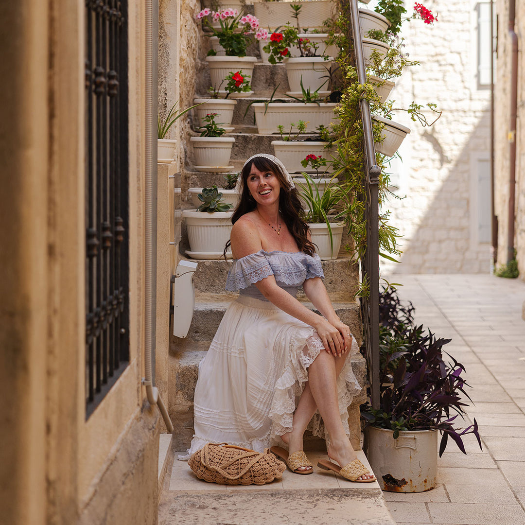 Woman sitting on a staircase with plants in an urban setting