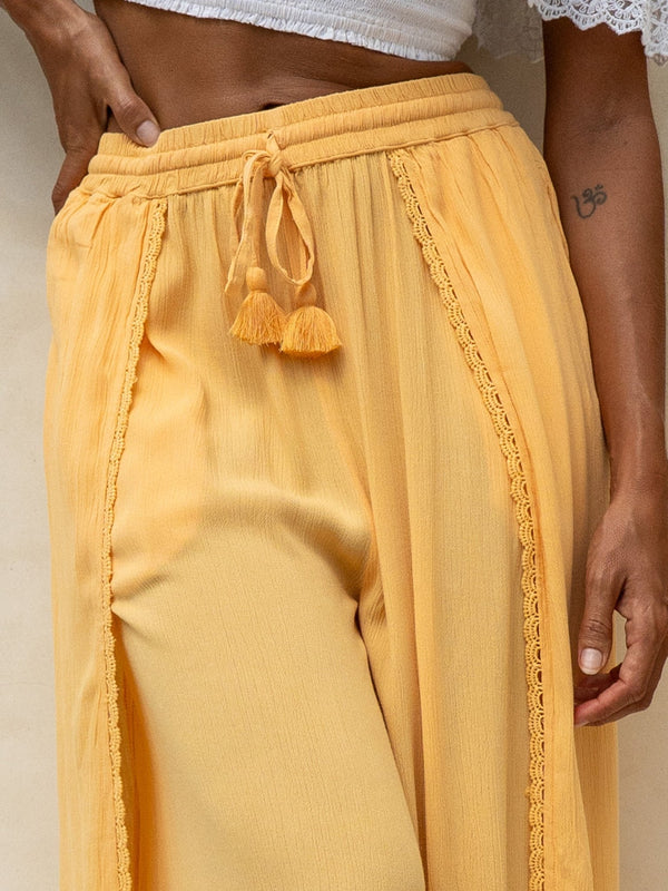 Yellow pants with tassel details on a neutral background