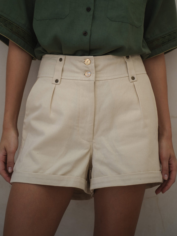 Beige shorts worn with a green shirt against a neutral background