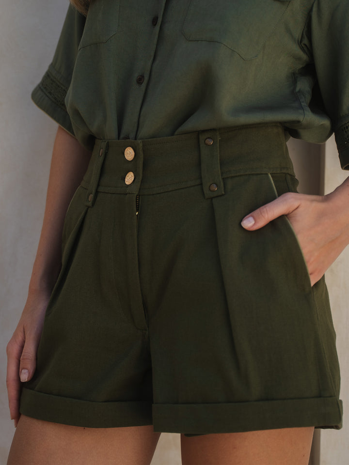 Person wearing a green shirt and shorts against a neutral background