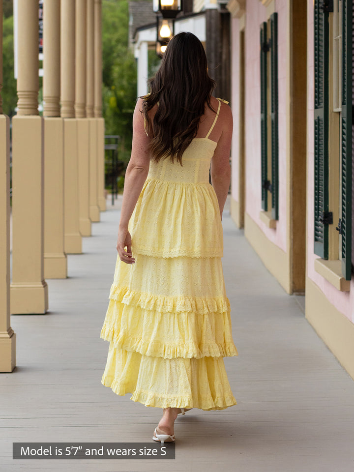 Woman wearing butter yellow Florence maxi dress with shiffli embroidery, square neckline, and tiered design