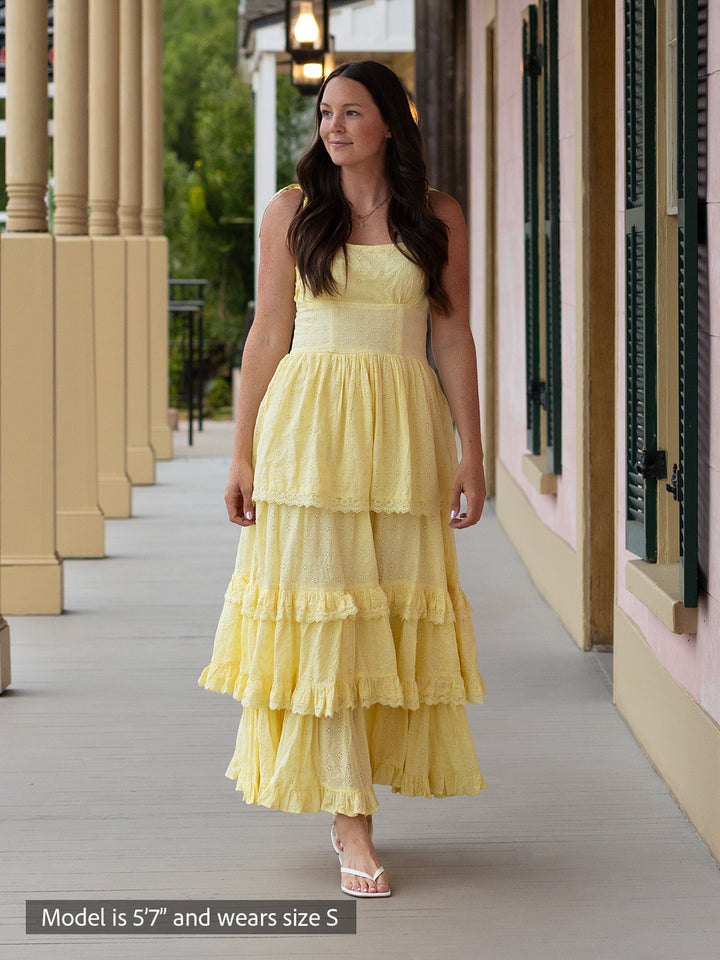 Woman wearing butter yellow Florence maxi dress with shiffli embroidery, square neckline, and tiered design