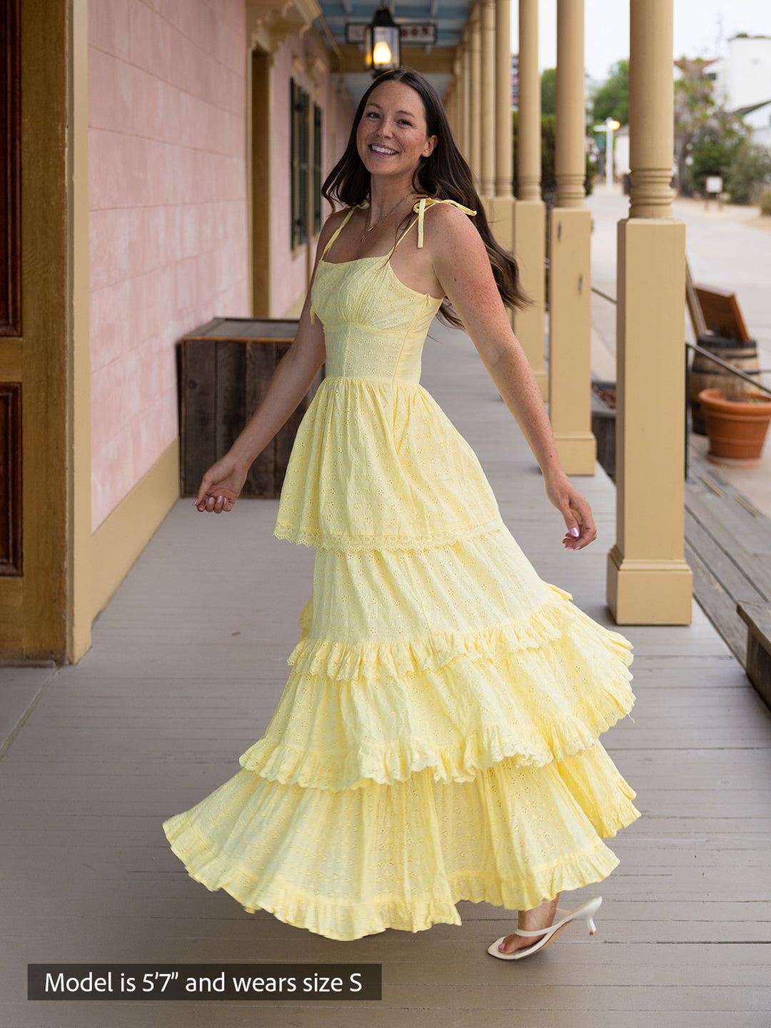 Woman wearing butter yellow Florence maxi dress with shiffli embroidery, square neckline, and tiered design