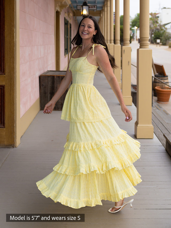 Woman wearing butter yellow Florence maxi dress with shiffli embroidery, square neckline, and tiered design