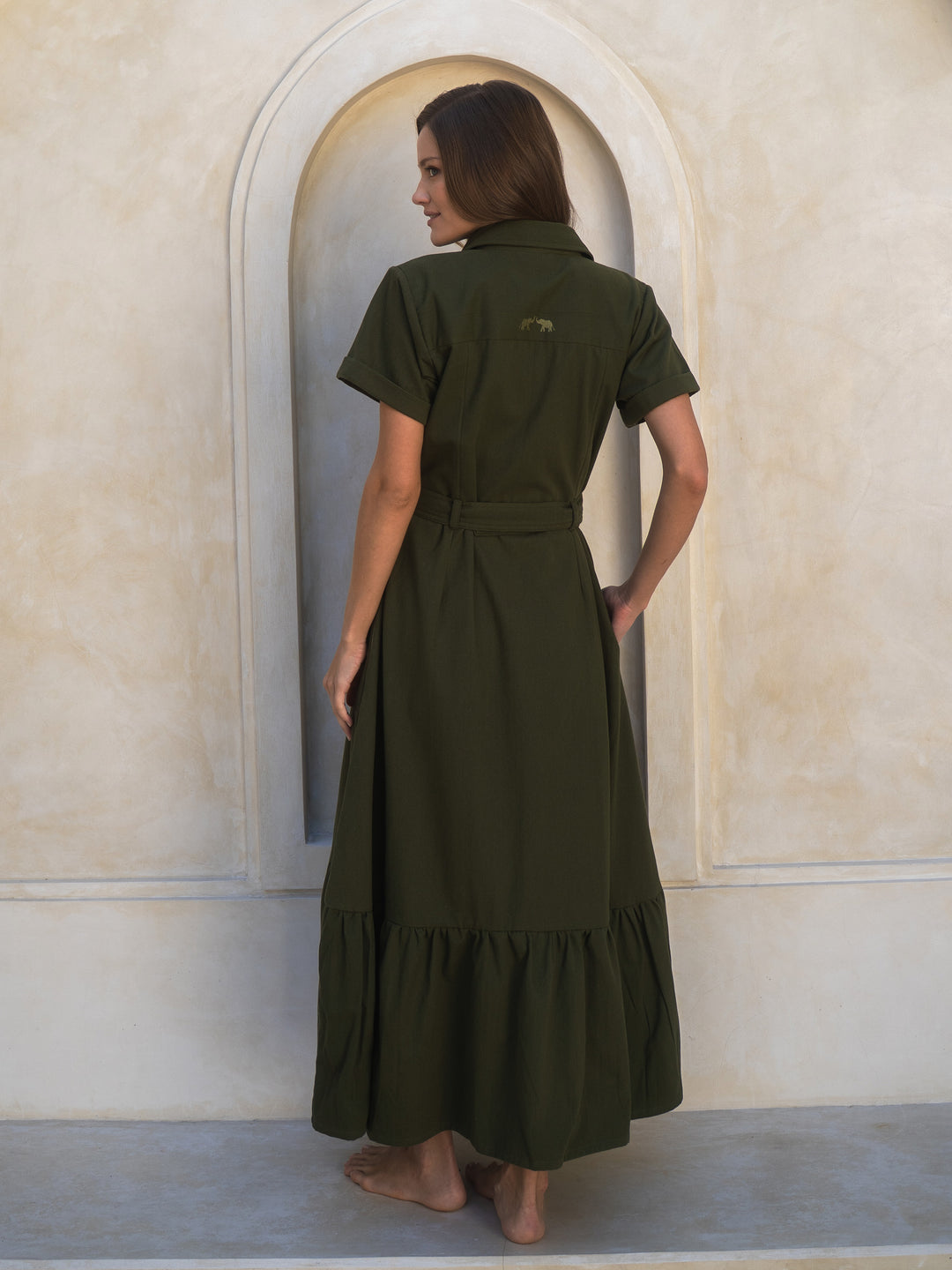 Woman wearing a green dress standing in front of an arched doorway.
