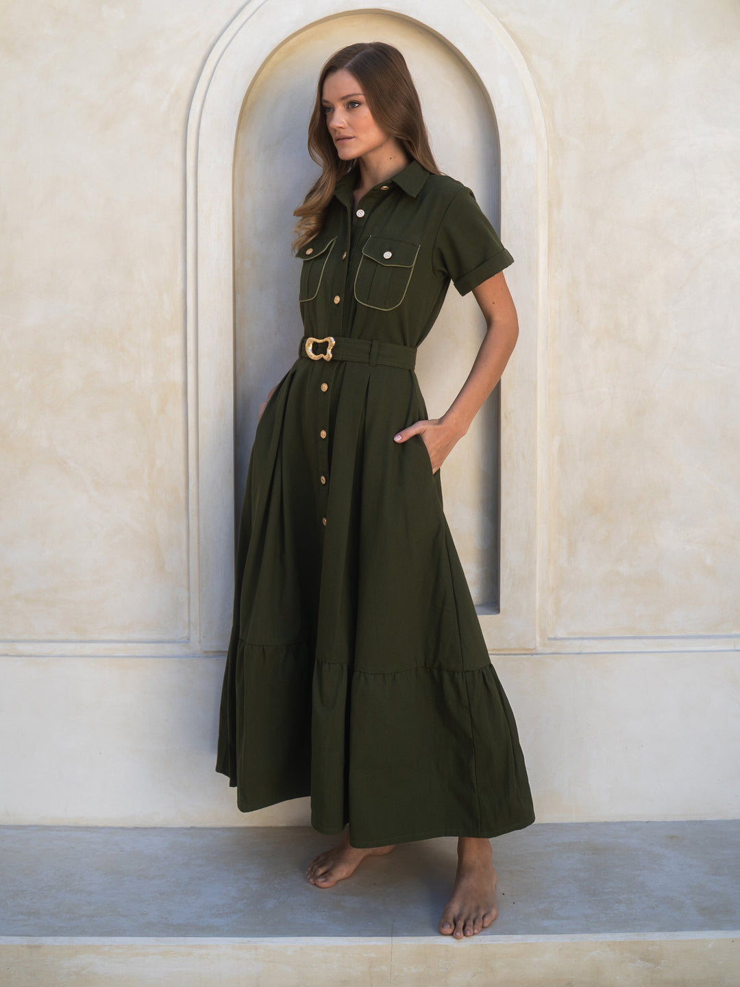 Woman wearing a green dress standing in front of an arched doorway.