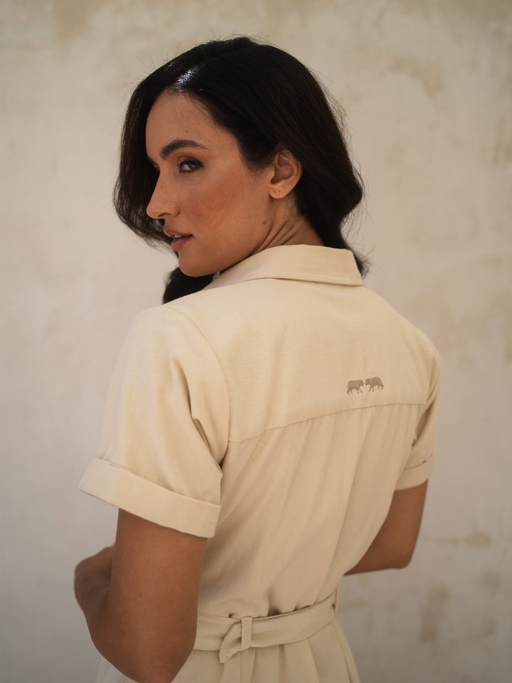 Woman wearing a beige dress with a logo on a plain background