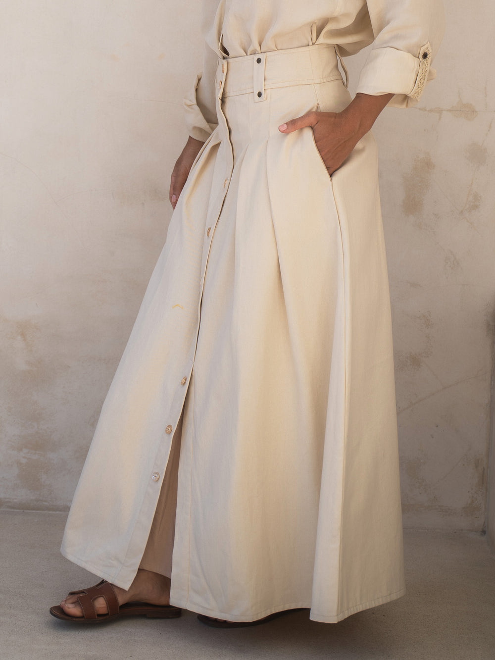 Person wearing a long beige coat against a neutral background