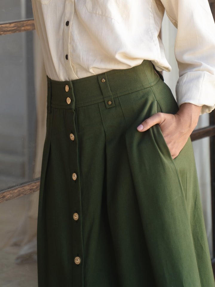 Green skirt with button details worn by a person, against a neutral background
