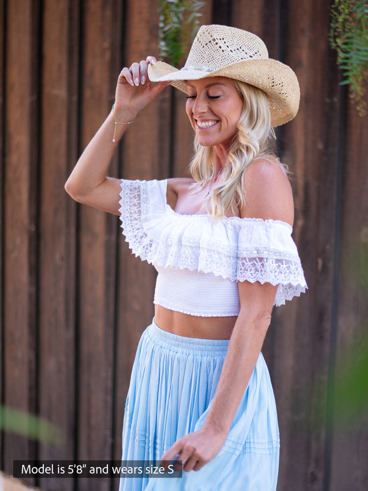 women wearing a White off-shoulder smocked crop top with ruffled neckline and lace-trim sleeves