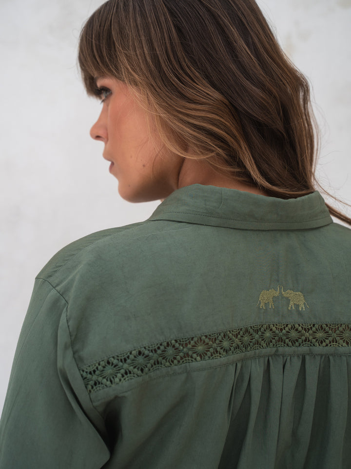 Woman wearing a green shirt with embroidery on a white background