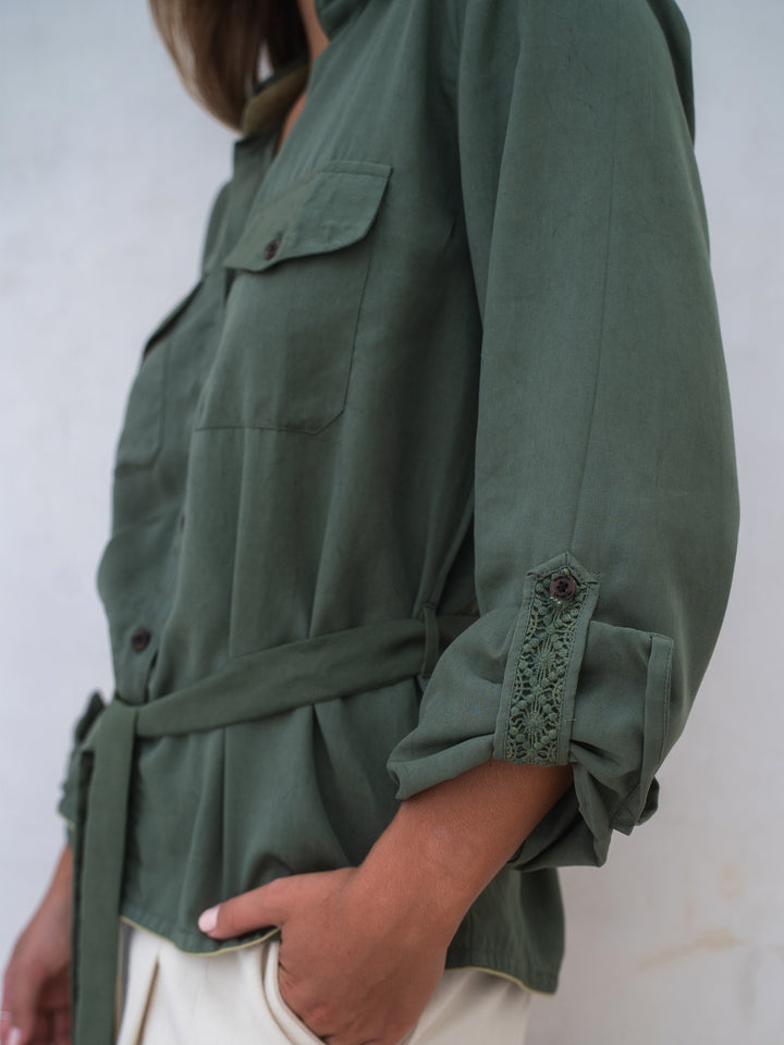Green jacket with lace details on cuffs against a white background