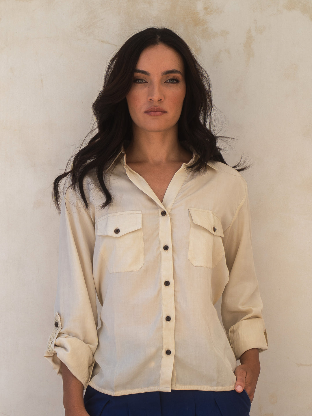 Woman wearing a beige shirt against a plain background