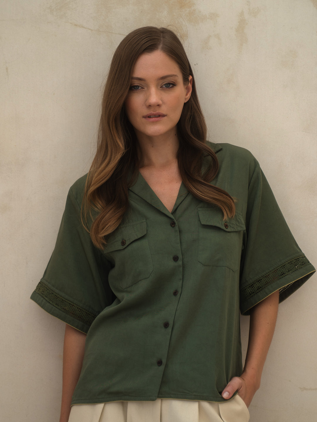 Woman wearing a green shirt against a beige wall