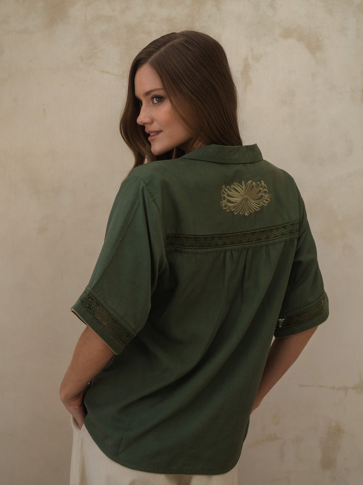 Woman wearing a green shirt with a decorative patch on a beige background