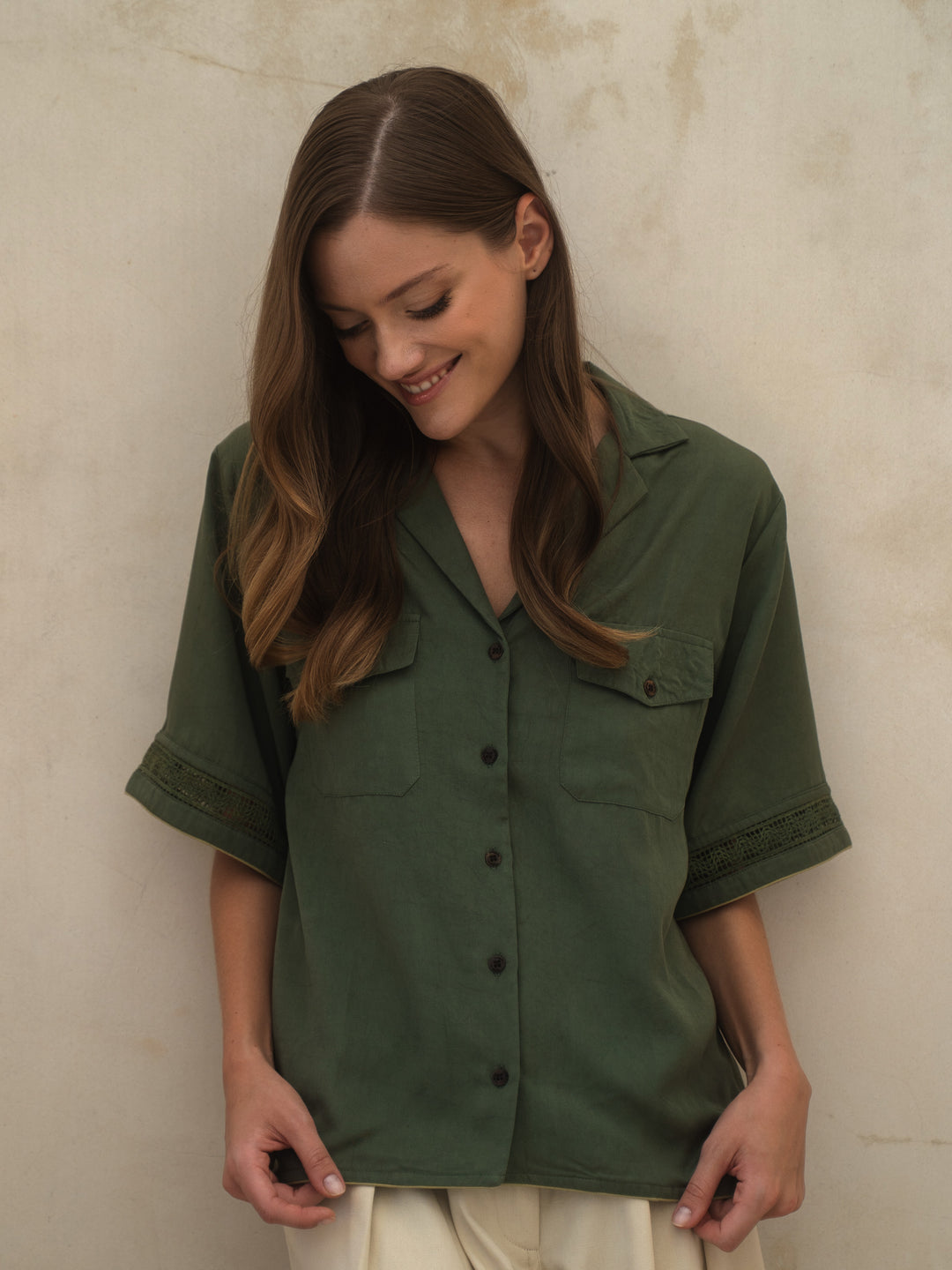 Woman wearing a green shirt against a beige wall