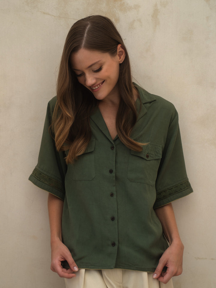 Woman wearing a green shirt against a beige wall