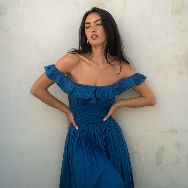Woman wearing a blue off-shoulder dress against a light background