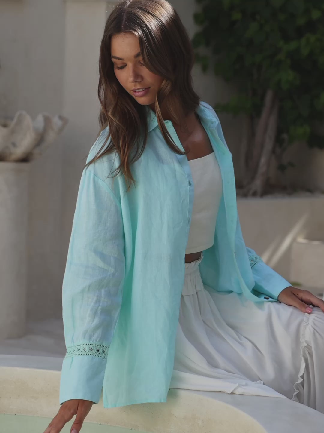 Woman wearing a light blue blouse with lace details in an elegant indoor setting.